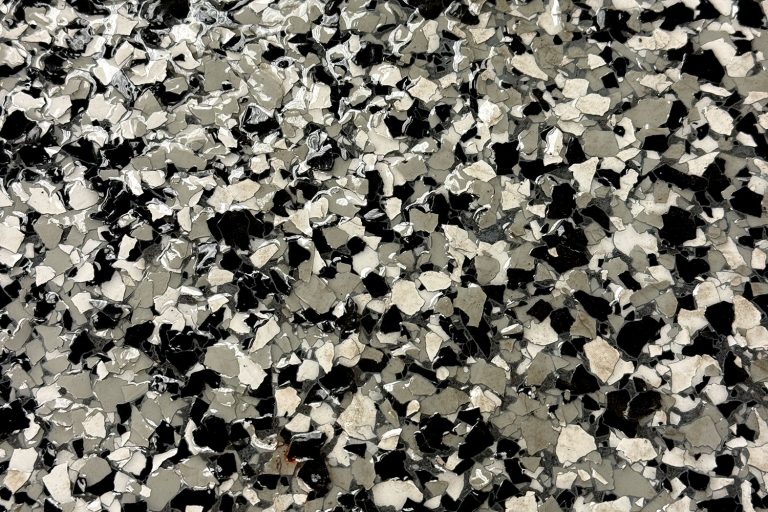 close up of black white and gray flakes in an epoxy basement floor