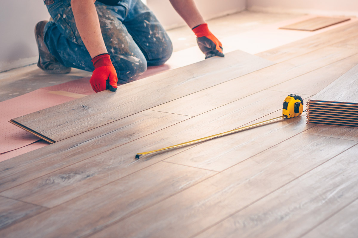 A worker installs flooring planks.