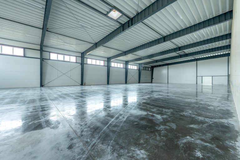 A large, open, industrial warehouse featuring polished concrete floors