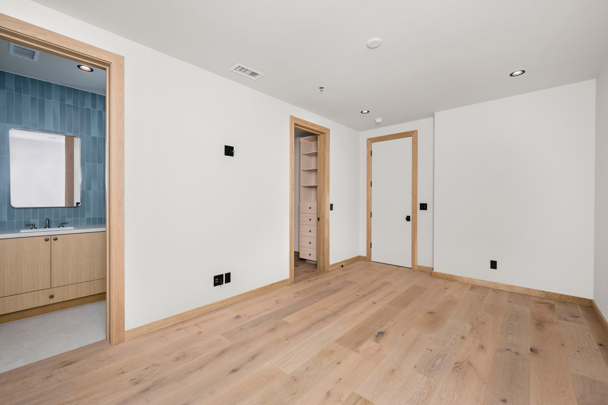 A bedroom with unfinished wood flooring.
