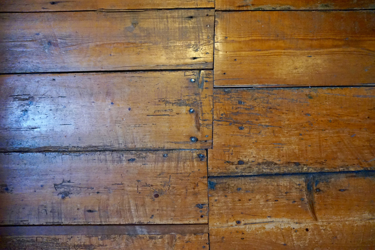 A close up of worn wooden floors in need of replacing.